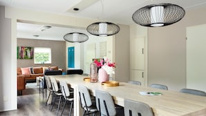 A modern dining area with a long wooden table, grey upholstered chairs, and black pendant lights. - House in Vlagtwedde With Sauna and Hot Tub (Vlagtwedde)