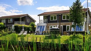 A residential area with two houses, a grassy yard, and a pond. - House in Vlagtwedde With Sauna and Hot Tub (Vlagtwedde)