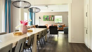 A modern kitchen with a long wooden countertop, black chairs, and pendant lights. - House in Vlagtwedde With Sauna and Hot Tub (Vlagtwedde)