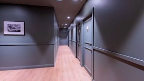 A hallway with dark walls, wooden flooring, and doors with numbered signs. - Les Appartements de Babel Vieux Port (Marseille)