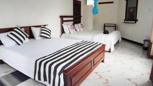 Ein Hotelzimmer mit zwei Betten, einem Holzkopfteil, einem Moskitonetz, einem Spiegel und einem Fliesenboden.