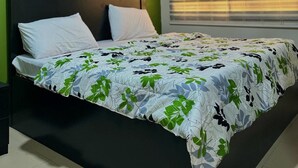 Un dormitorio con cama, paredes verdes, una ventana con persianas y un equipo de aire acondicionado.