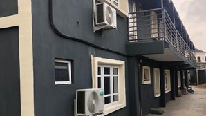 Un edificio con varias unidades de aire acondicionado, un balcón y un suelo empedrado de ladrillo.