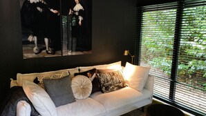 Ein modernes Wohnzimmer mit einem weißen Sofa, gemusterten Kissen und einem Gemälde von zwei Personen.