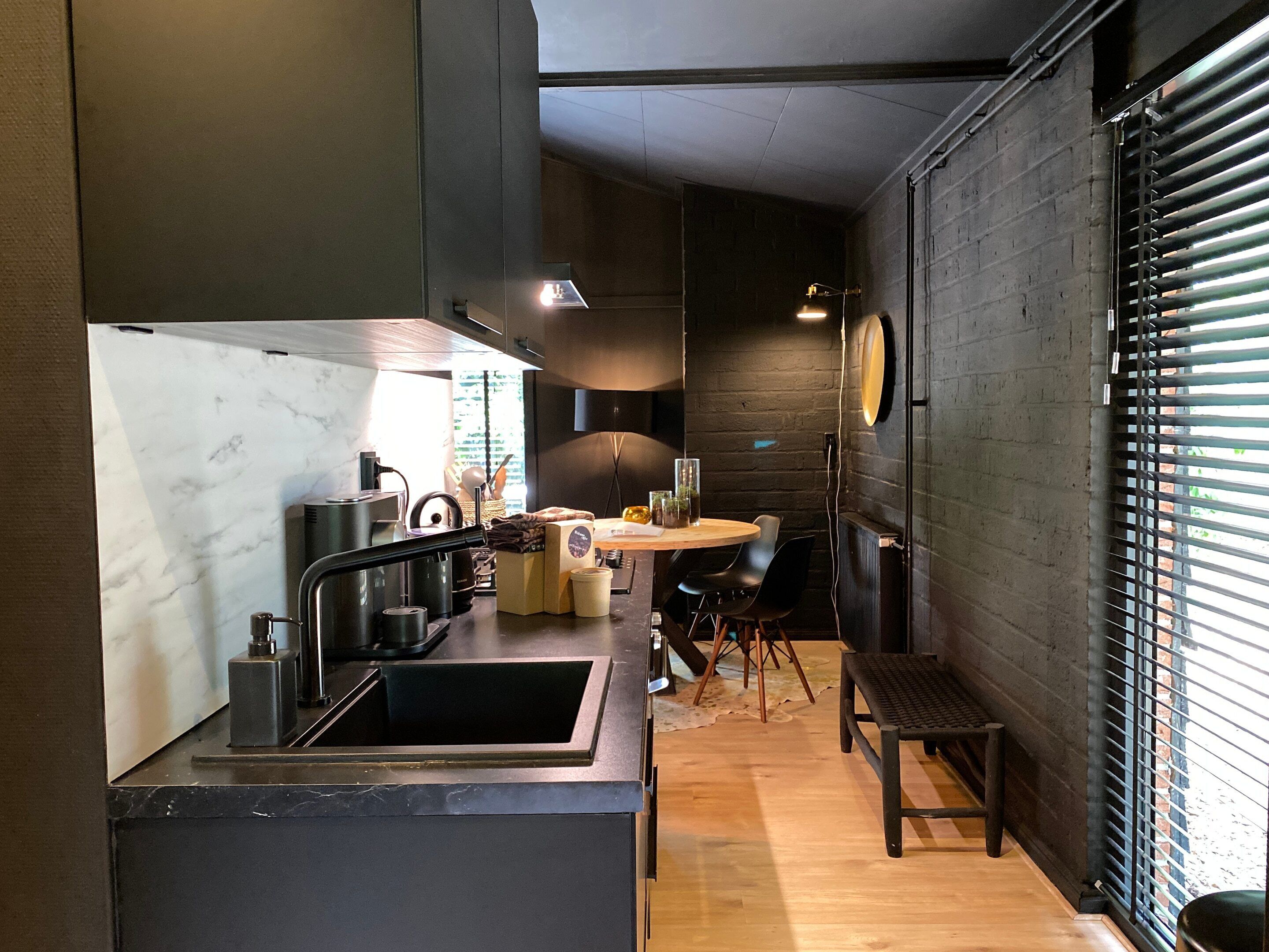 A modern kitchen with a marble countertop, a sink, and a dining area with a round table and chairs.