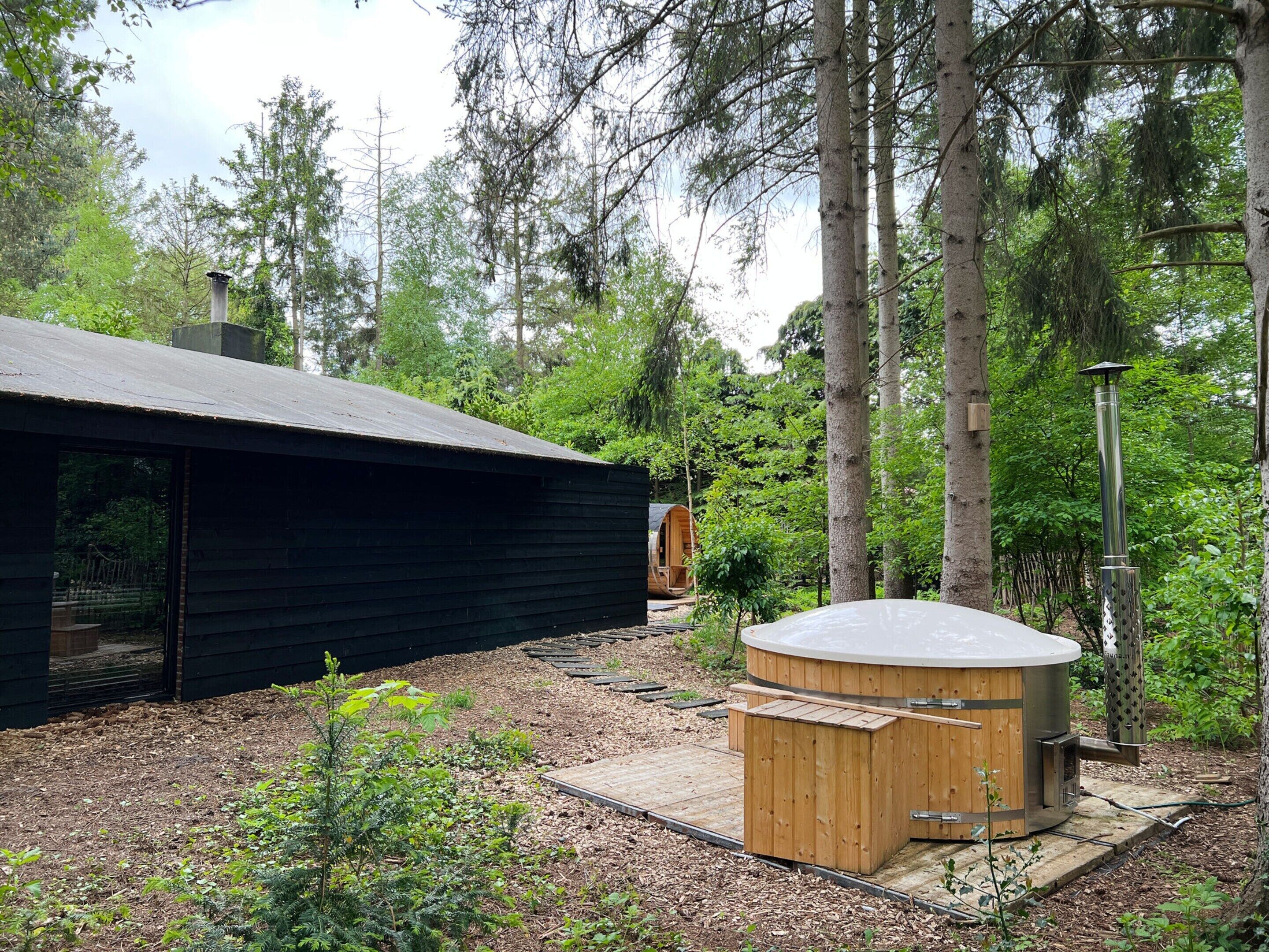 Een chalet met houten buitenkant, een jacuzzi en een terras, omgeven door bomen.