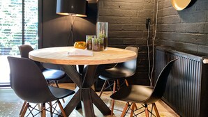 Ein runder Holztisch mit schwarzen Stühlen, einer Stehlampe und Topfpflanzen.