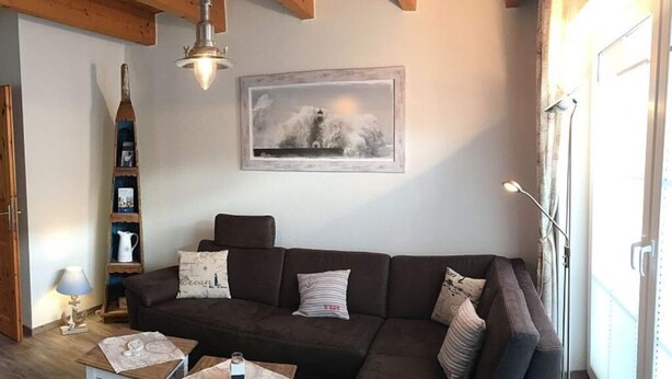 A cozy living room with a dark brown sofa, two small wooden tables, and a bookshelf. - Dat Onnen's Hus - Burhave 3 (Butjadingen)