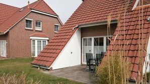 A residential building with a sloped red-tiled roof, brick walls, and a garage with a white door. - Dat Onnen's Hus - Burhave 3 (Butjadingen)
