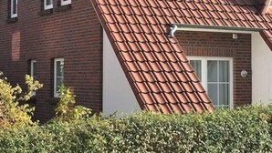 A two-story building with a red-tiled roof and brick walls. - Dat Onnen's Hus - Burhave 3 (Butjadingen)
