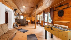 A cozy room with a wooden ceiling, a sofa, a foosball table, and a dining area with chairs and a table. - Farmhouse Bramberg Near Wildkogelbahn (Bramberg am Wildkogel)