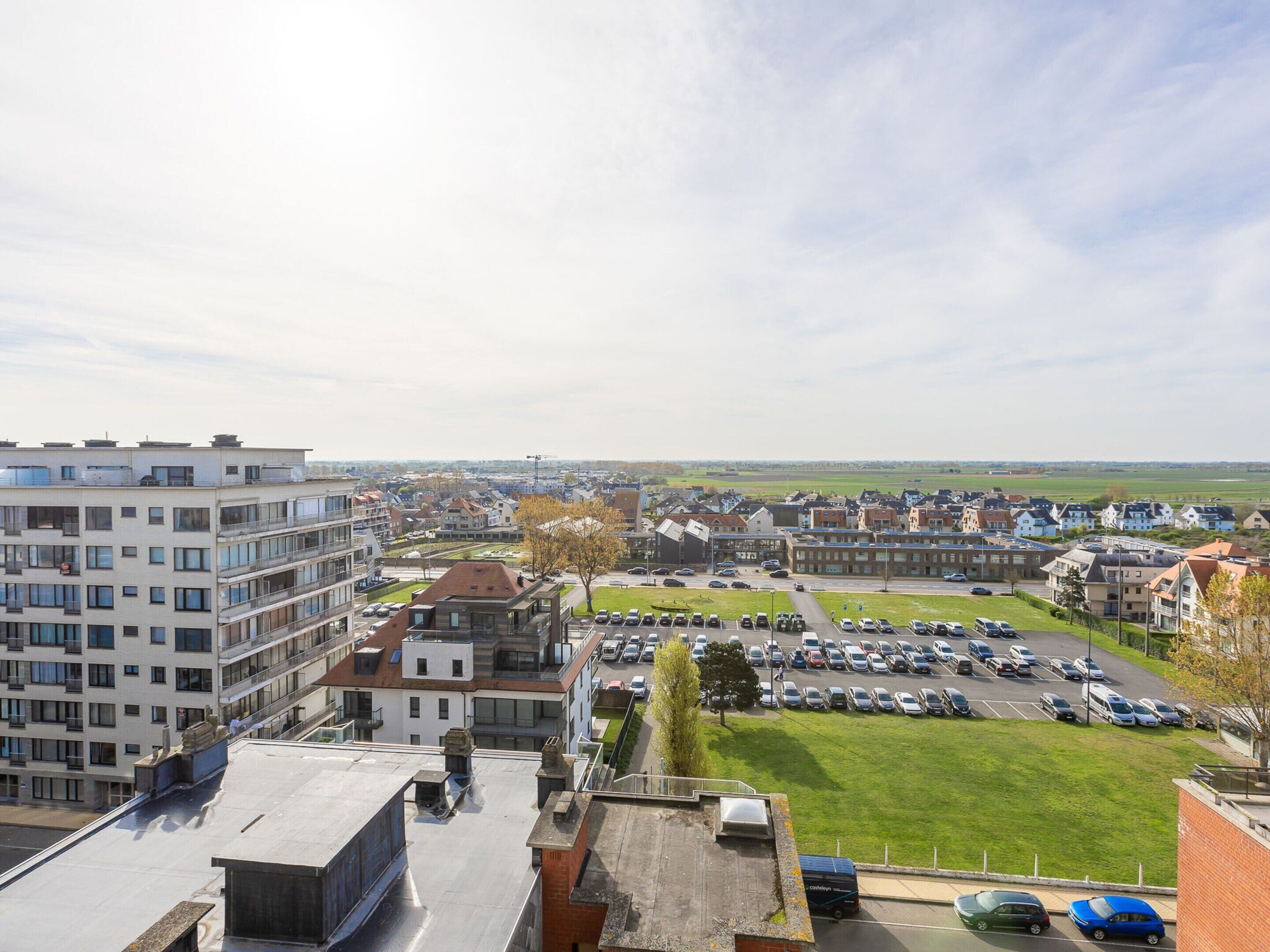 A residential area with modern buildings, a parking lot, and a view of the surrounding landscape.