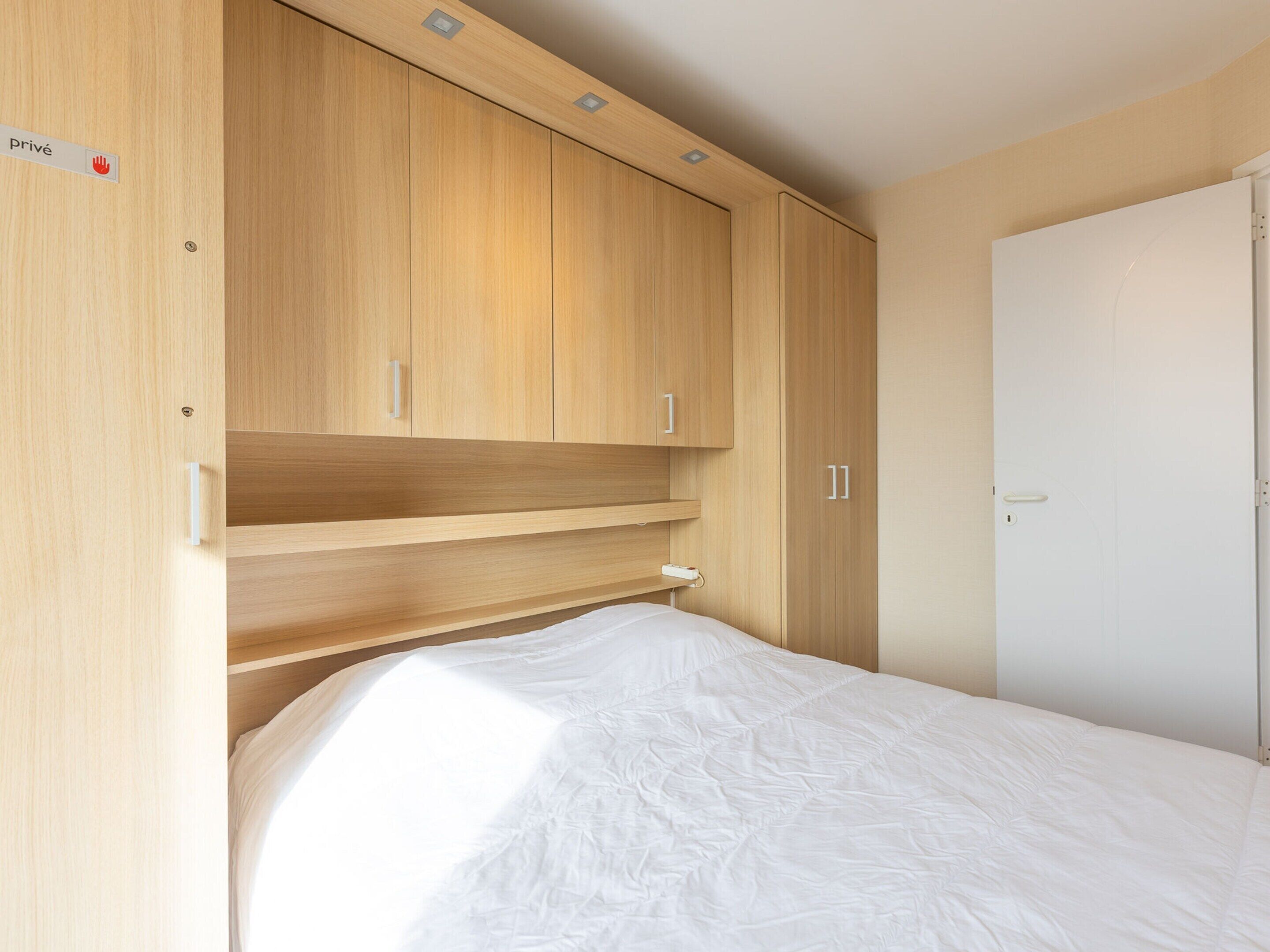 A bedroom with a bed, wooden wardrobe, and a door.
