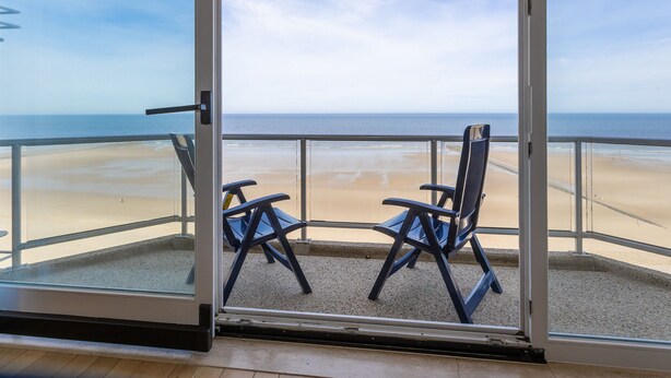Un balcon avec deux chaises donnant sur une plage.