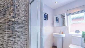 Une salle de bain moderne avec une douche à parois de verre, un lavabo blanc et des toilettes.