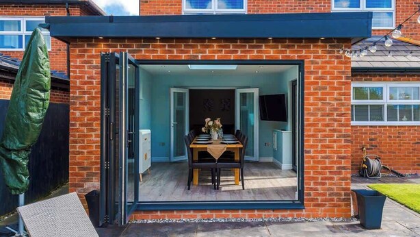 Une maison moderne dotée d’une porte en verre qui donne sur un espace repas.