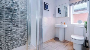 Une salle de bain moderne avec une douche à parois de verre, un lavabo blanc et des toilettes.