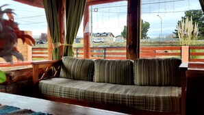 A cozy seating area with a plaid sofa and a wooden table. - Cabañas Clarita (Dina Huapi)