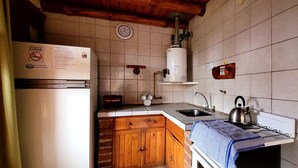 A kitchen with a refrigerator, sink, kettle, and wooden cabinets. - Cabañas Clarita (Dina Huapi)