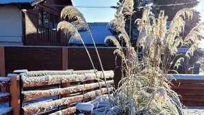 A wooden sign with the text "Tabernas Clarita" in a rustic setting with snow-covered ground and plants. - Cabañas Clarita (Dina Huapi)