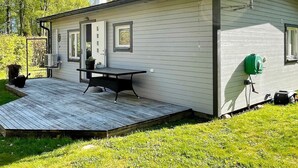 A single-story house with a deck, a small outdoor table, and a green lawn. - 4 Star Holiday Home in Solvesborg (Sölvesborg)