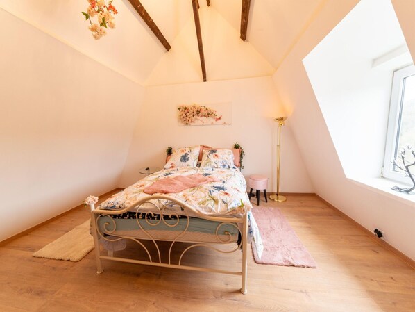 Una camera da letto con un letto, una lampada da terra, una finestra e un'opera d'arte appesa al muro.