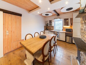 Una cucina moderna con mobili in legno, un tavolo da pranzo con sedie e una parete d'accento in pietra.