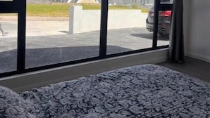 Huone, jossa on suuri ikkuna, josta avautuu näkymä parkkialueelle ja rakennuksiin.