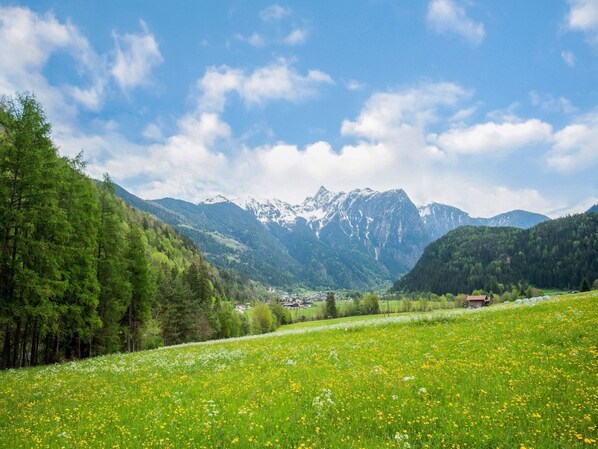 A mountainous landscape with a valley, a small settlement, and a clear sky.
