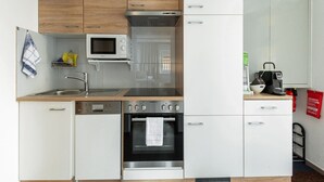A compact kitchen with wooden cabinets, a built-in microwave, a stainless steel oven, and a coffee maker. - Nice Apartment in Sautens With a Cozy Terrace (Sautens)