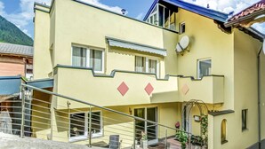 A two-story building with a balcony, a satellite dish, and a staircase leading to the entrance. - Nice Apartment in Sautens With a Cozy Terrace (Sautens)