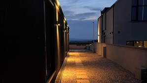 Un camino que lleva a un edificio, con superficie de grava y piedras de madera.