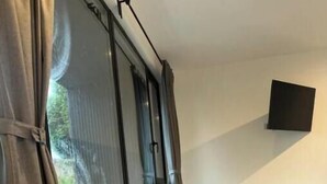 Una habitación moderna con ventanas amplias, un televisor de pantalla plana en la pared y suelo de madera.