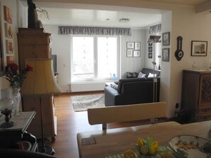 A living room with a sofa, a lamp, a wooden cabinet, and a window with curtains. - Appealing Apartment in Sankt Aldegund (Sankt Aldegund)