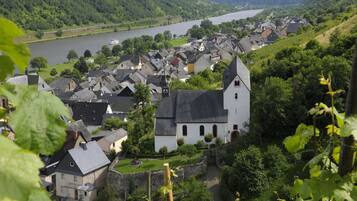 Eine Stadt mit einem markanten weißen Kirchengebäude, umgeben von Wohngebäuden, einem Fluss im Hintergrund und üppiger Vegetation.