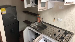 Une cuisine de taille réduite équipée d’un réfrigérateur, d’un évier et d’une cuisinière.