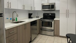 A modern kitchen with white cabinets, stainless steel appliances, and a black countertop. - 7th FL spacious 1 bedroom  (Hollywood)