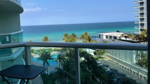 A balcony with a view of the ocean, a pool area, and a parking lot. - 7th FL spacious 1 bedroom  (Hollywood)