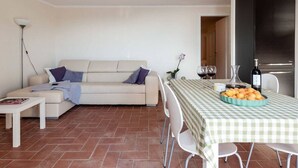 A living room with a sofa, a dining table with a checkered tablecloth, and a kitchen area with a refrigerator. - Casina di Savolano Comfortable Holiday Residence (Livorno)