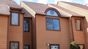 A two-story building with a symmetrical facade, a central entrance with a door, and a small porch area. - Relax at This Mountain View Condo in the Estates! (Campton)