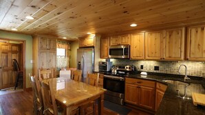 A wooden kitchen with a dining table, chairs, a refrigerator, a microwave, an oven, and a sink. - Relax at This Mountain View Condo in the Estates! (Campton)