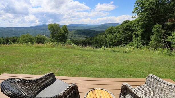 A deck with wicker chairs overlooking a grassy landscape and distant hills. - Relax at This Mountain View Condo in the Estates! (Campton)