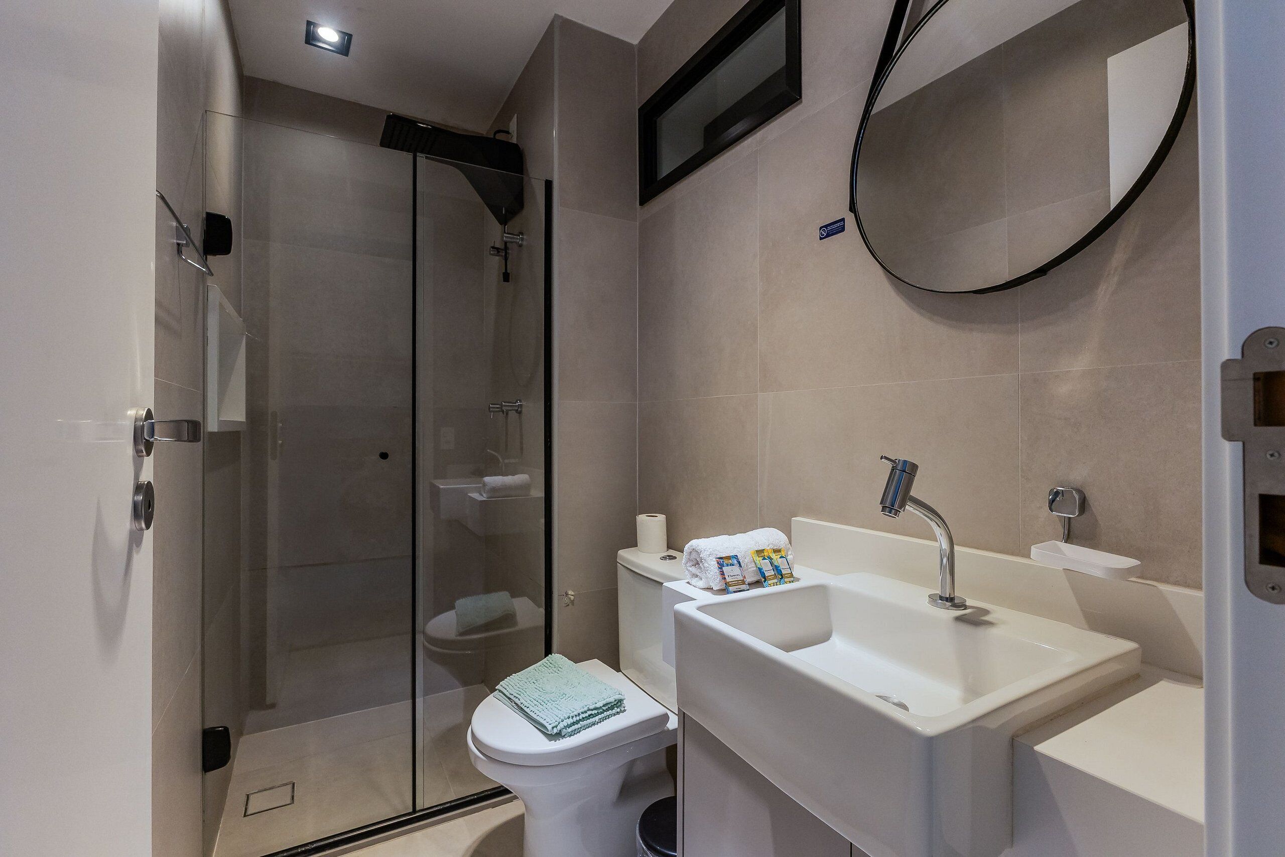 A modern bathroom with a glass shower enclosure, a toilet, and a sink with a mirror.