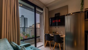 Eine moderne Wohnung mit Sofa, Essbereich und einem Fernseher, der 'NETFLIX' zeigt.