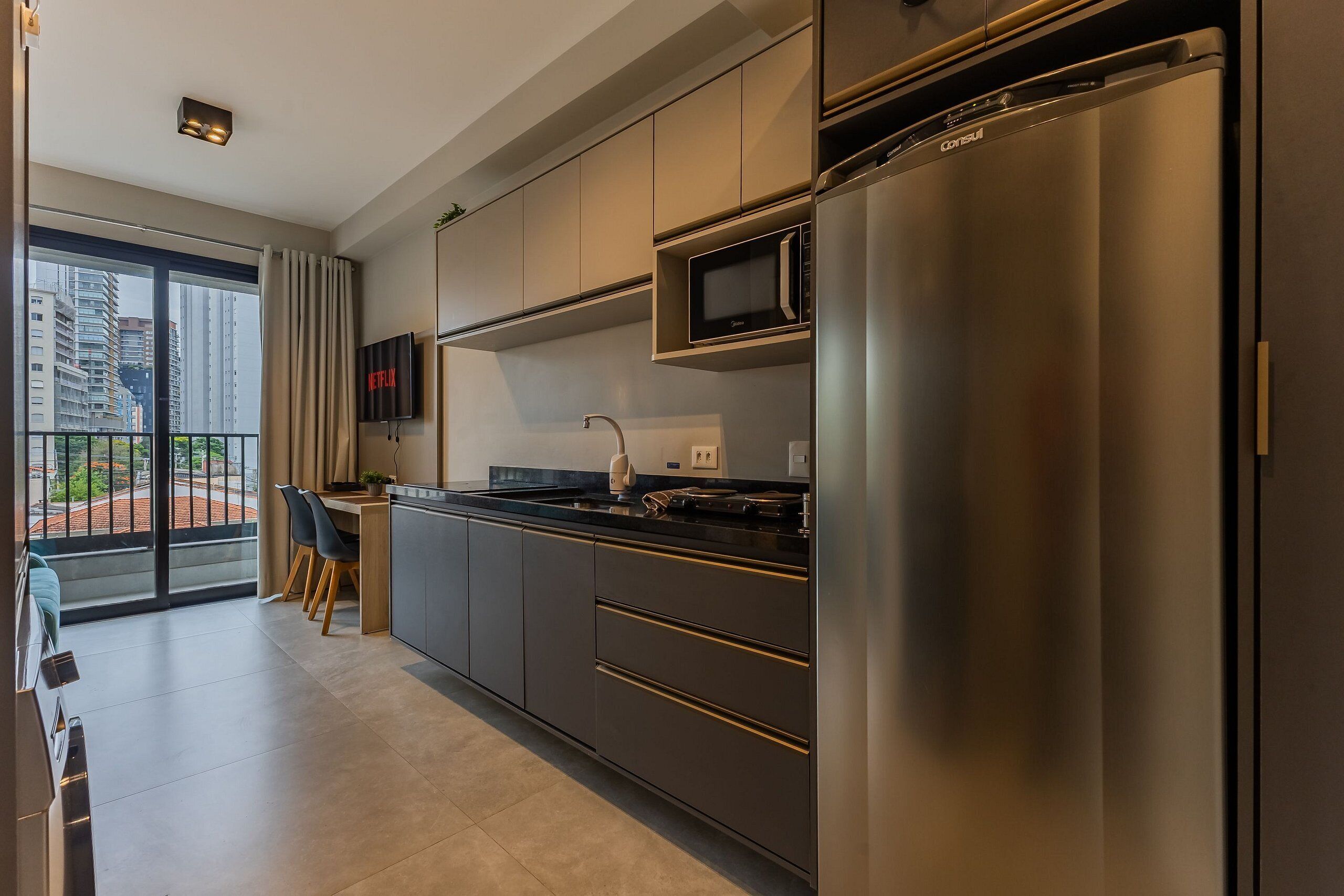 A modern kitchen with a stainless steel refrigerator, microwave, and a dining area with a table and chairs.