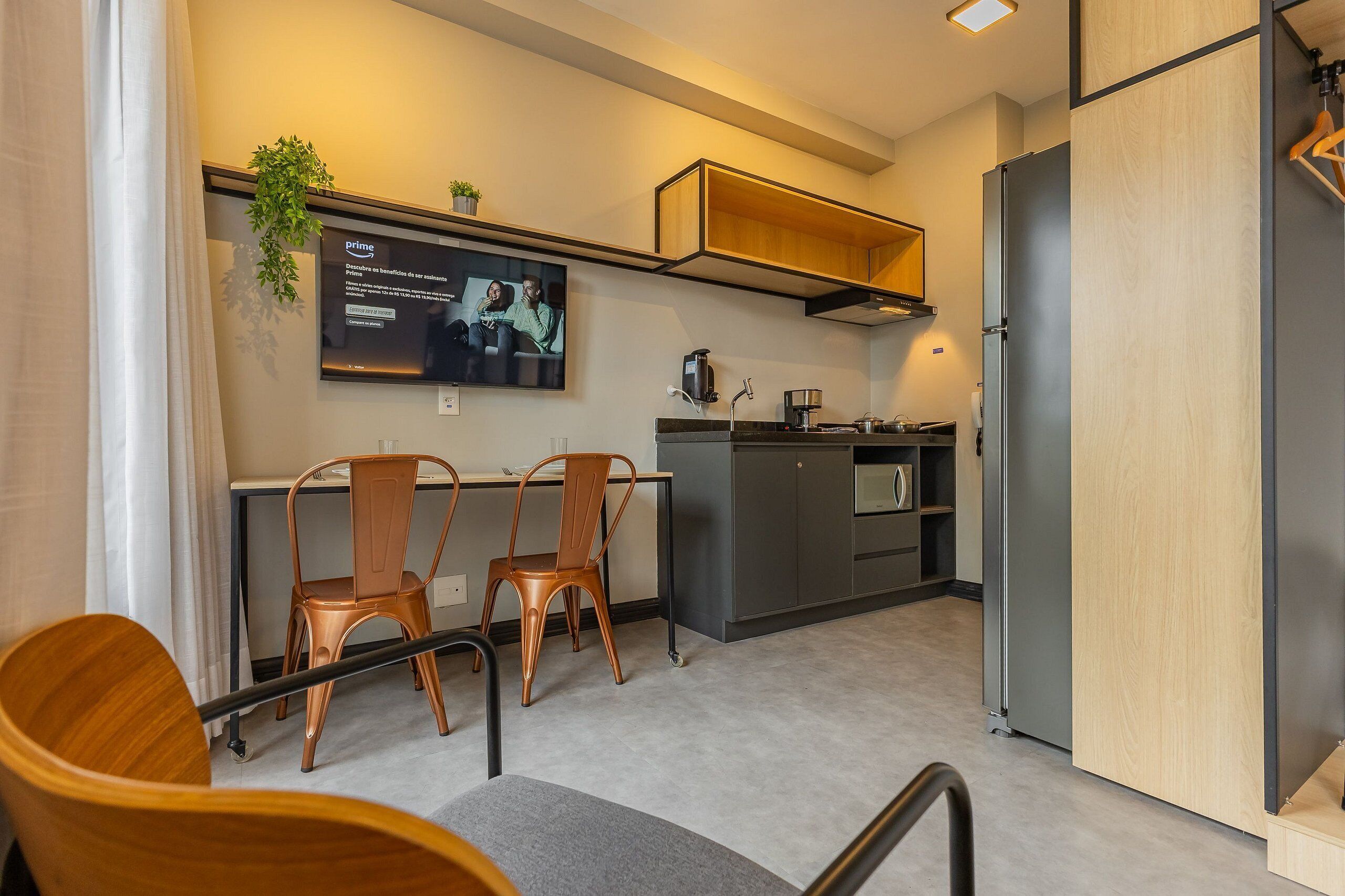 A modern kitchen with a built-in oven, a coffee machine, and a small dining area with two chairs.