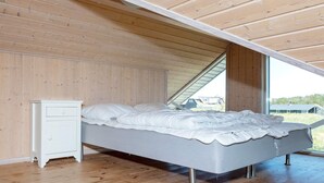 Un dormitorio con cama, mesita de noche y ventana.
