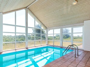 A swimming pool with a view of the outdoors through large windows. - 12 Person Holiday Home in Pandrup (Pandrup)