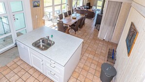 Una cocina con pileta, alacenas y una zona de comedor con mesa y sillas.