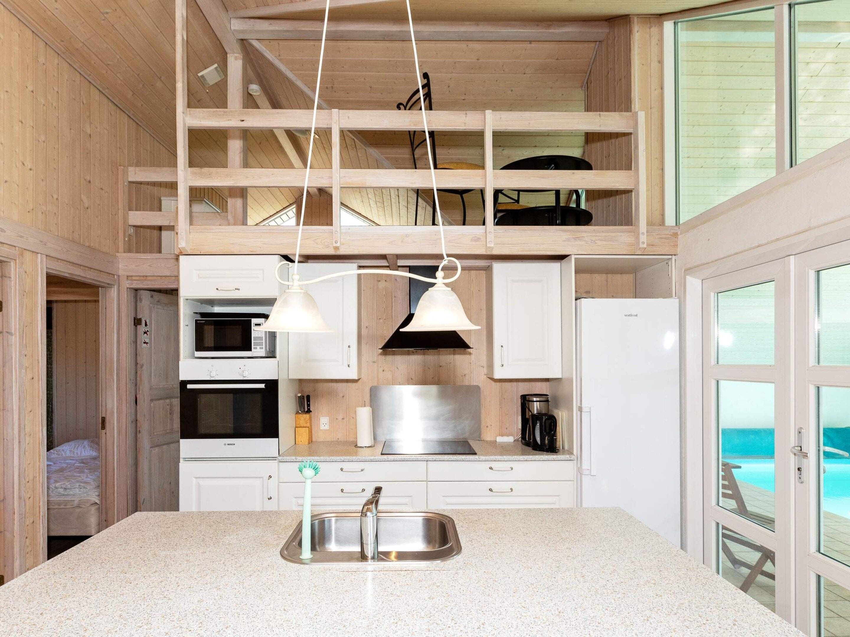 A compact kitchen with a sink, stove, and overhead lighting.